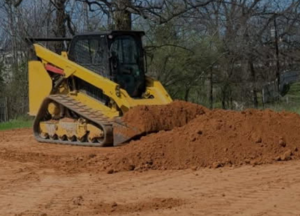 Excavator working on land clearing and grading for land management projects.